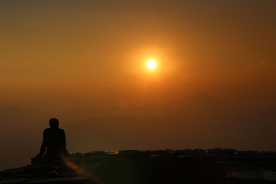 A serene silhouette sitting during a beautiful sunrise with a warm golden glow.